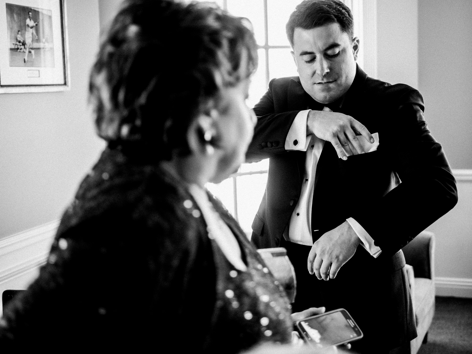 Ryan tucks in a kerchief as his mom watches on while they get ready for his wedding at the Seattle Tennis Club in Seattle, WA. Summer 2016. Photo by Seattle Wedding Photographers Jennifer Tai Photo Artistry.