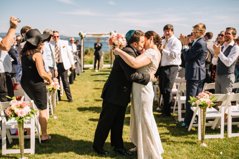 One more kiss for Joelle and Ryan while they walk down the aisle at the Seattle Tennis Club, Summer 2016. Photo by Seattle Wedding Photographers Jennifer Tai Photo Artistry.