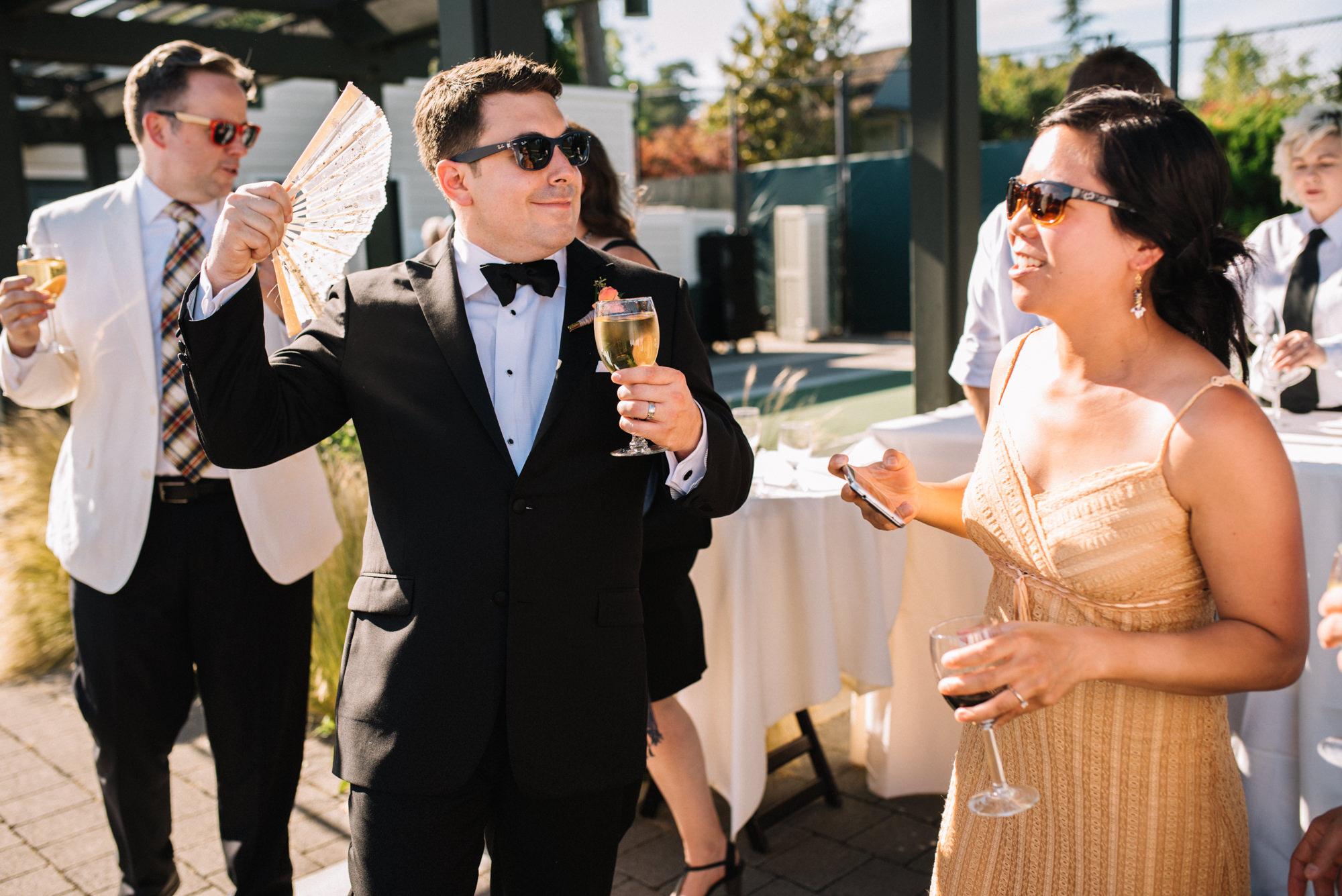 Ryan goofs around at their cocktail reception after the wedding ceremony at the Seattle Tennis Club, a wedding venue in Seattle. Summer 2016. Photo by Seattle Wedding Photographers Jennifer Tai Photo Artistry.