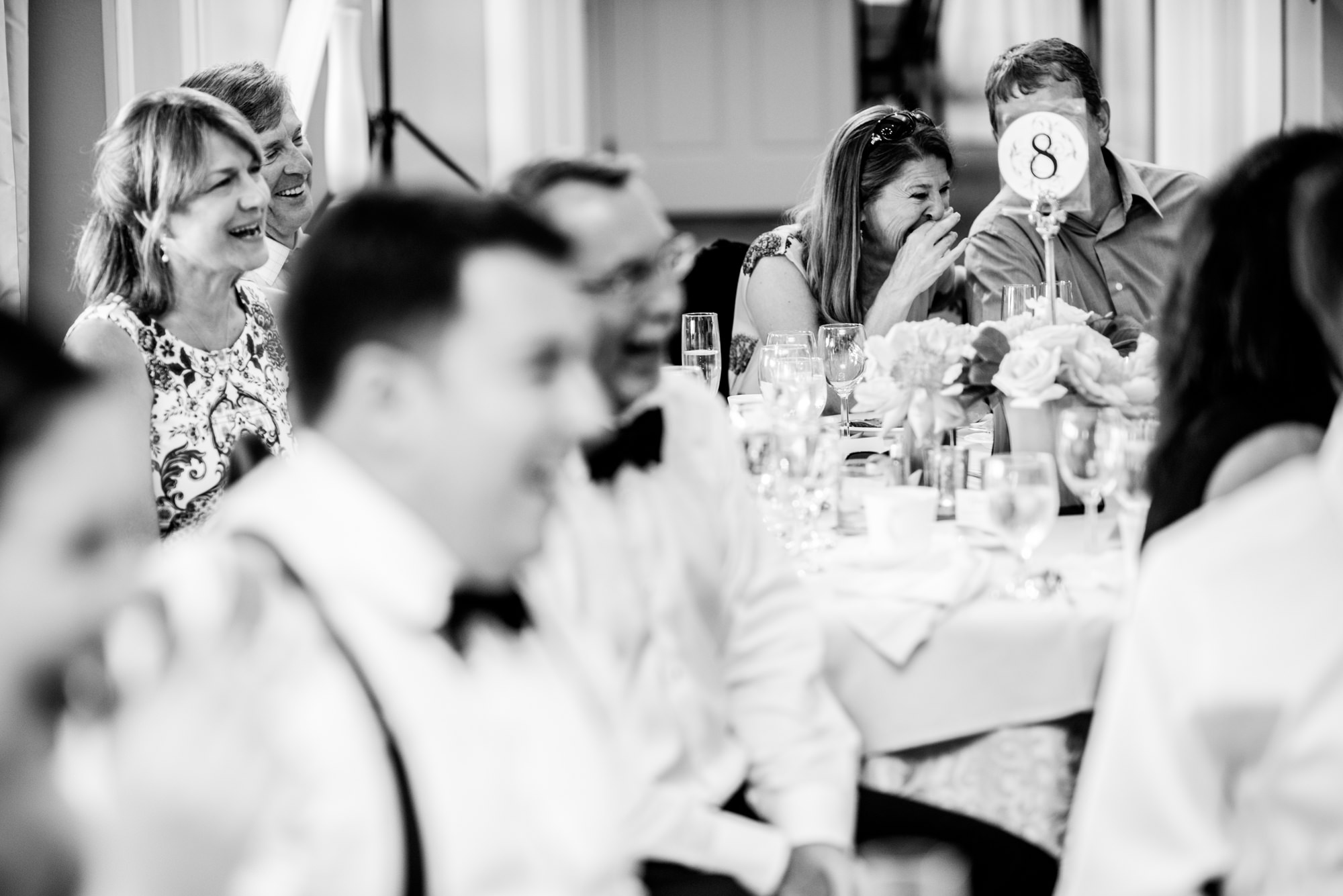 Guests laugh at the funny toast-rap performance by Joelle's siblings at Joelle and Ryan's wedding reception, held at the Seattle Tennis Club in the summer of 2016. Photo by Seattle Wedding Photographers Jennifer Tai Photo Artistry.