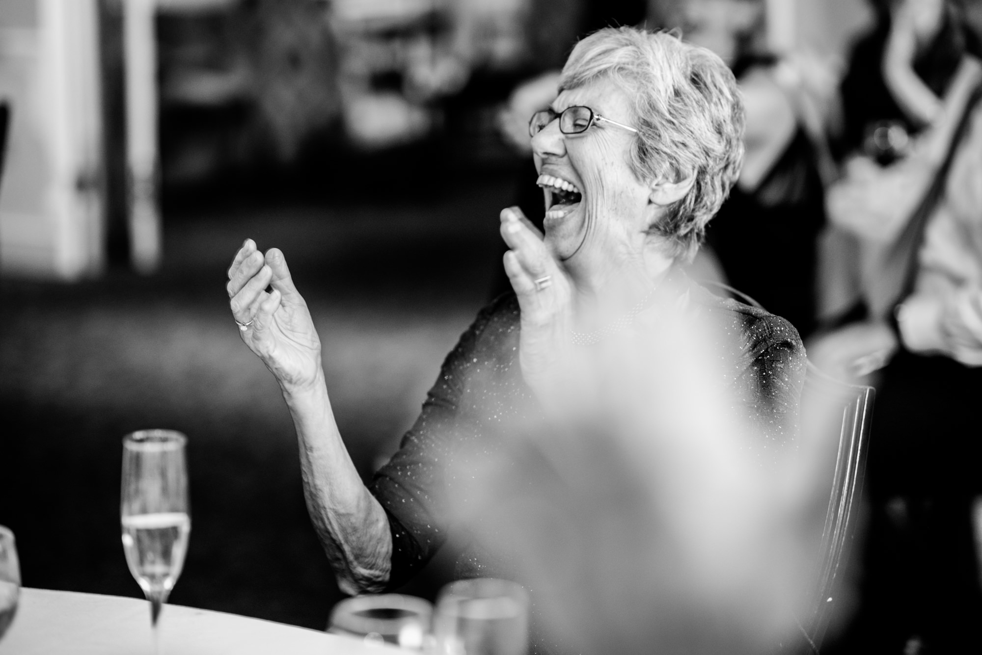 Joelle's mom also laughs at the funny performance at Joelle and Ryan's wedding reception at the Seattle Tennis Club, Summer 2016. Photo by Seattle Wedding Photographers Jennifer Tai Photo Artistry.
