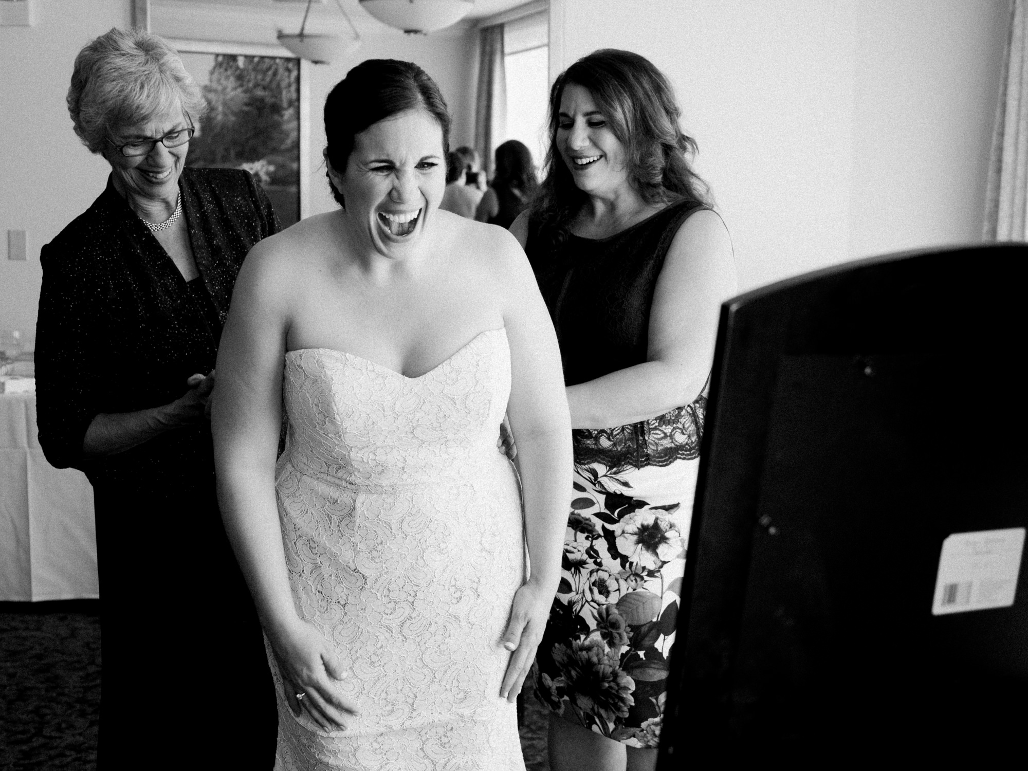 Joelle, the bride, reacts to her gown while getting ready with her sister and mom. They were getting ready at the Seattle Tennis Club, a wedding venue in Seattle, WA. Photo by Seattle Wedding Photographers Jennifer Tai Photo Artistry.