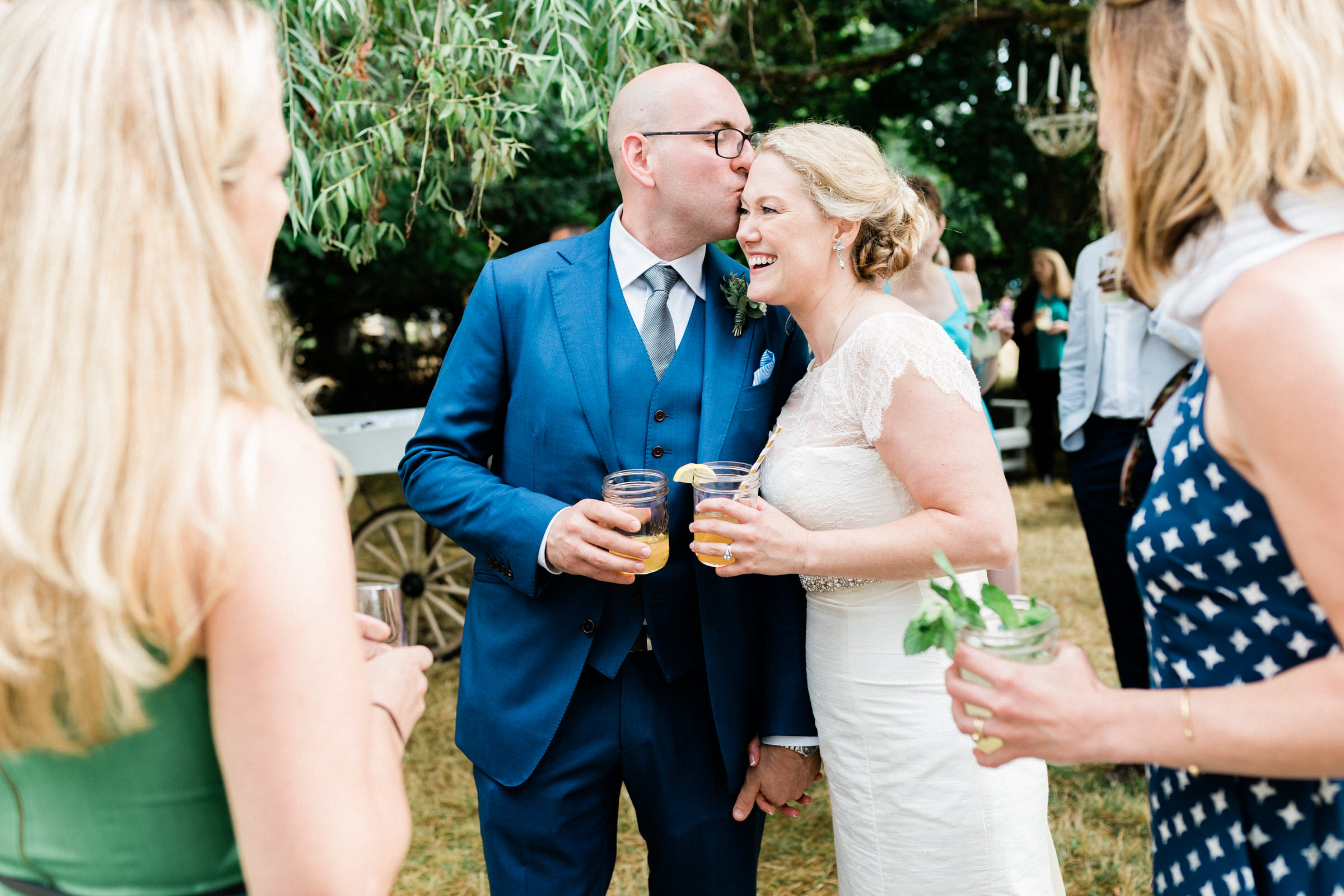 Wayfarer Whidbey Island Wedding: Groom Joe gives bride Sara a kiss while chatting with their guests