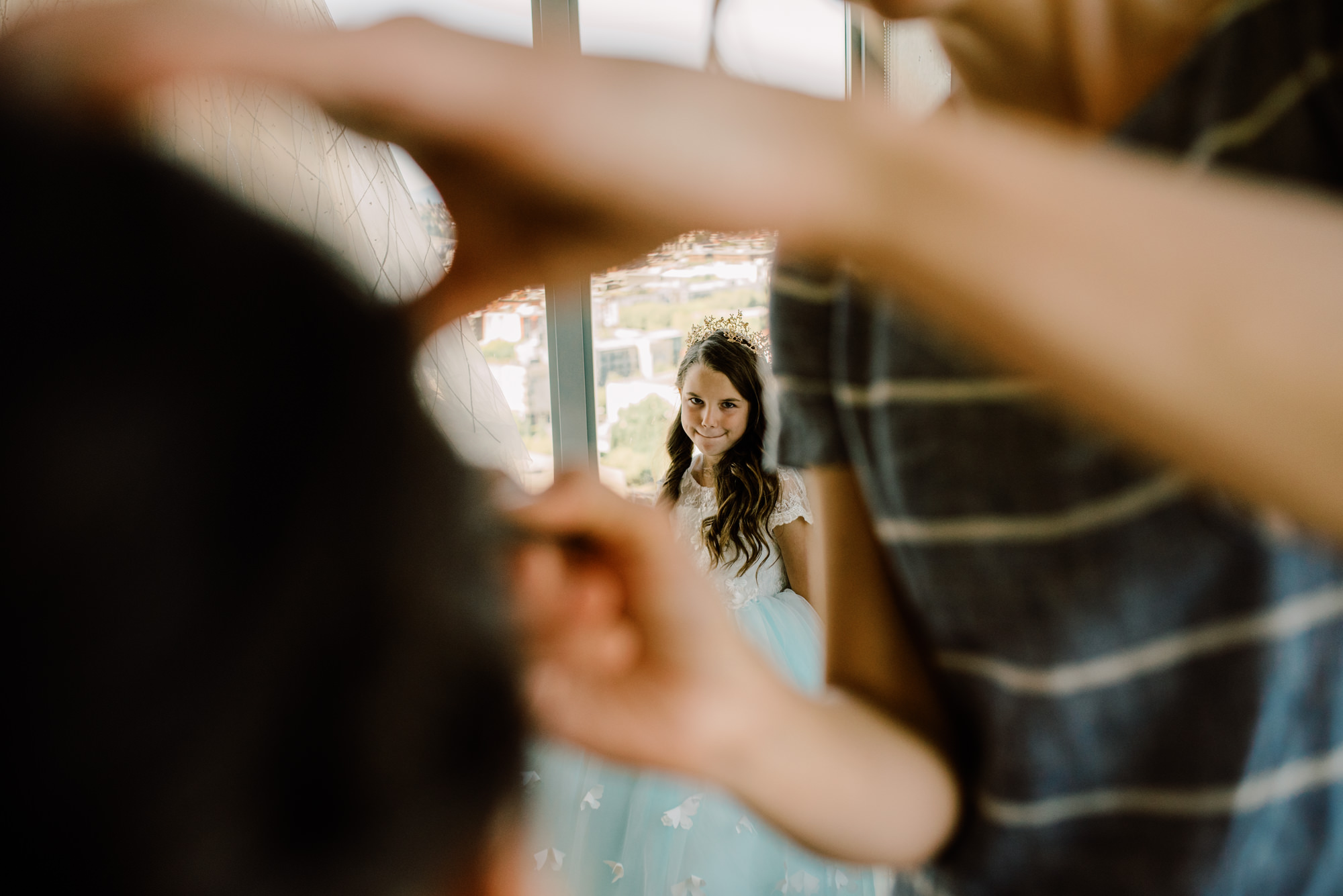 Flower girl looking at a bridesmaid getting makeup done