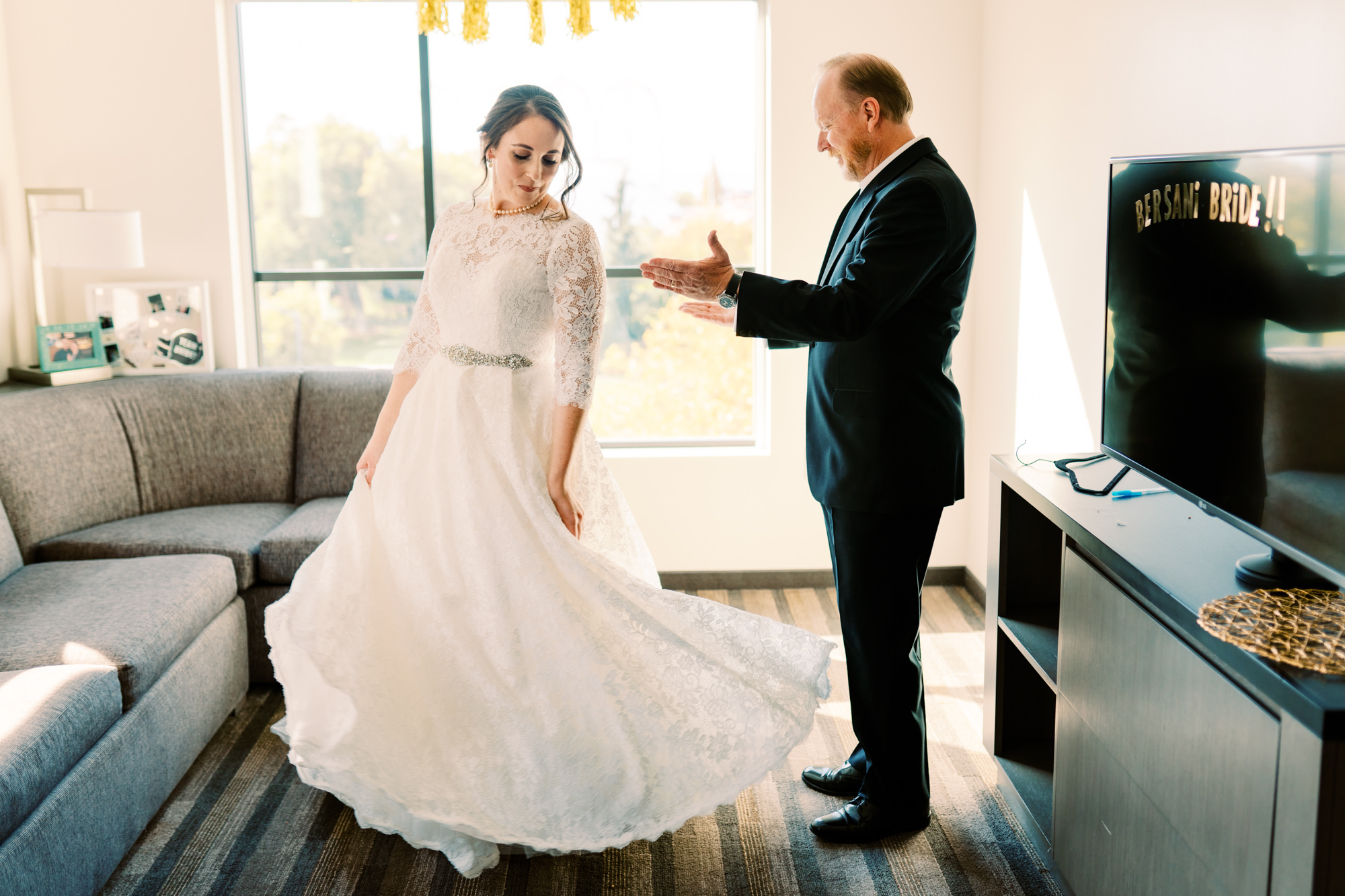 Father of the bride admires his daughter in her wedding gown