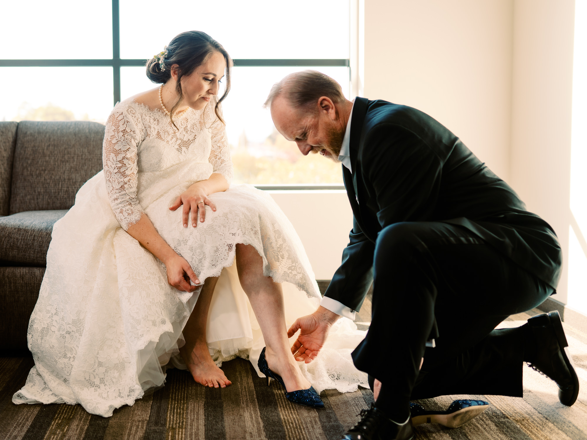 Father of the bride helps her put on her shoes
