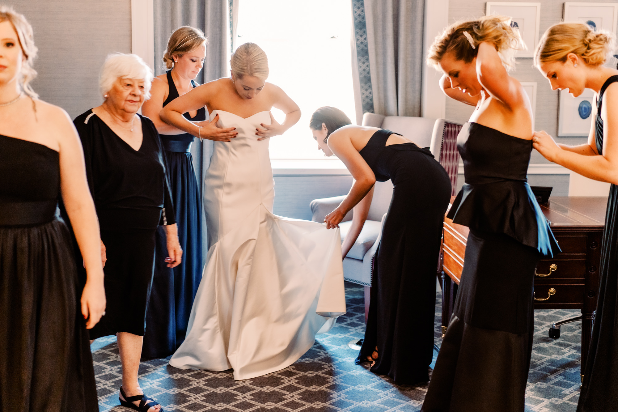 Bride Mary getting dressed with the help of her bridesmaids in classy black