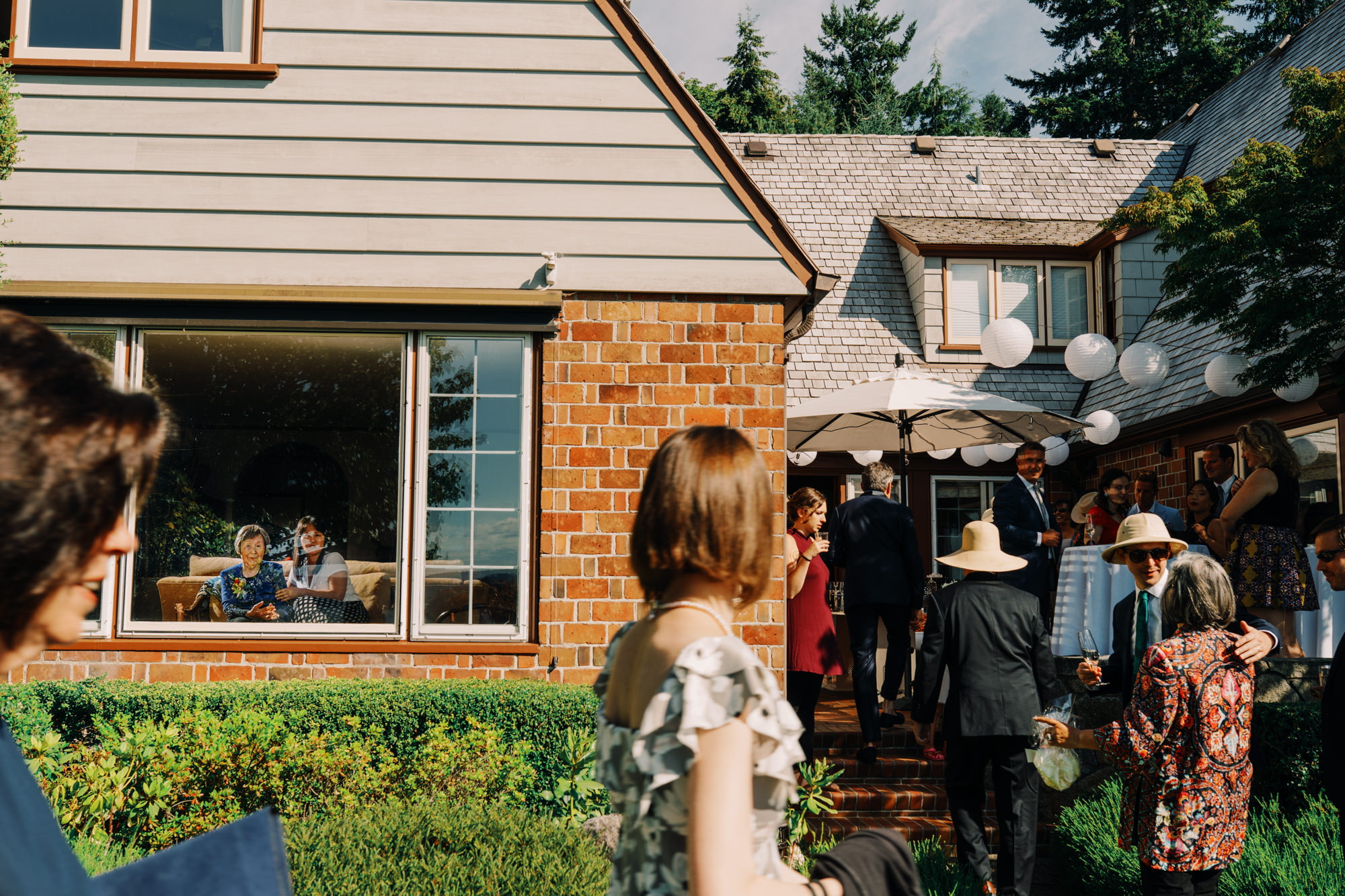 Guests arriving at the Wohns' home with grandma looking on at Jen and Sage's backyard garden wedding.